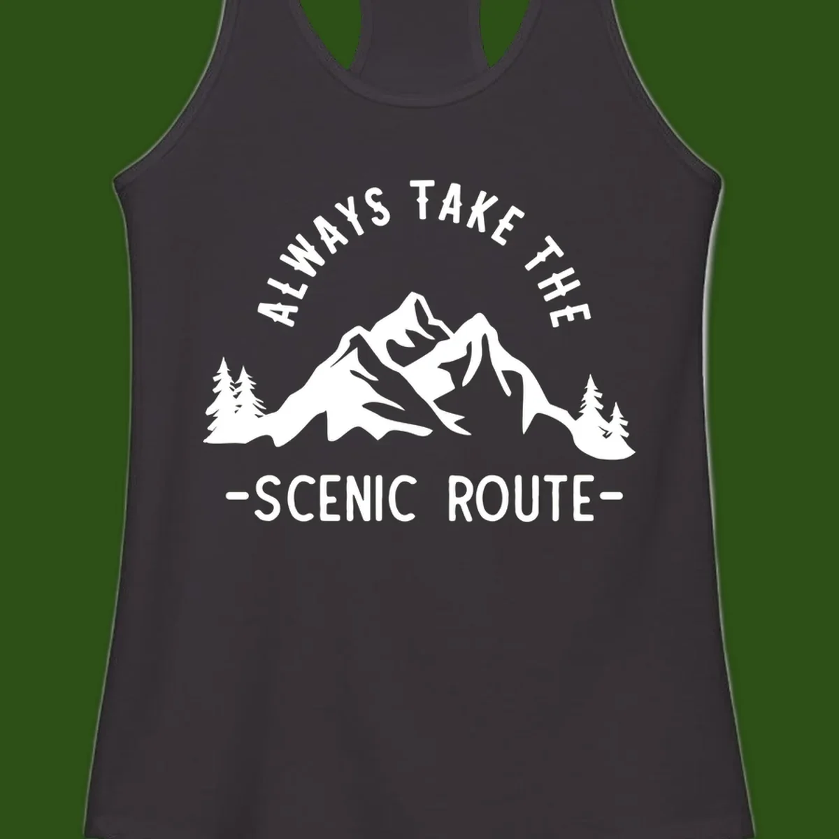Mountain landscape with evergreen trees and text reading 'Always Take The Scenic Route' in bold lettering