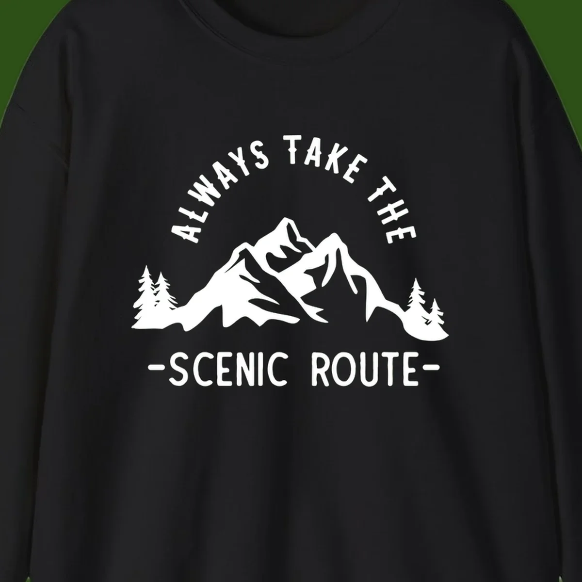 Mountain landscape with evergreen trees and text reading 'Always Take The Scenic Route' in bold lettering