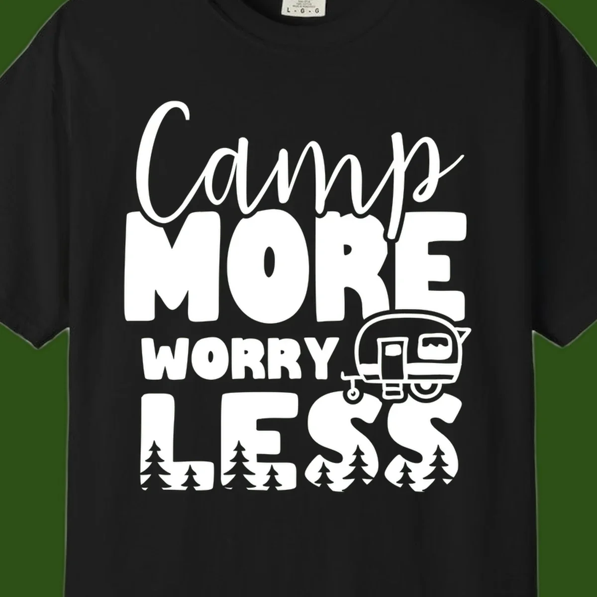 Camp More Worry Less design with flowing script text, camping trailer, and pine trees on gray background