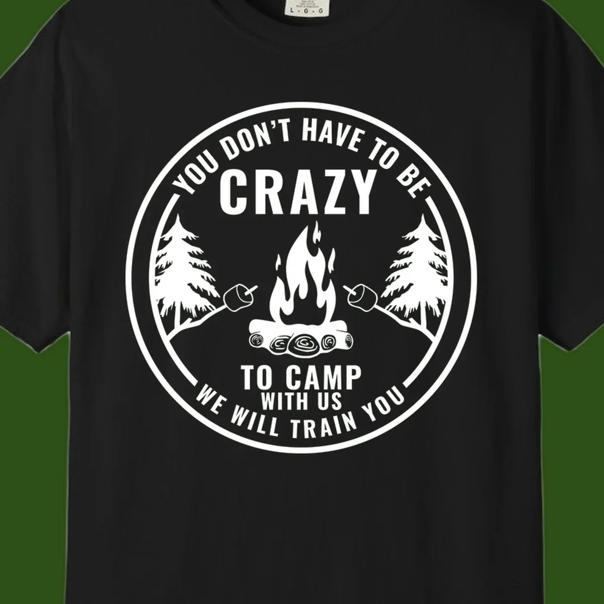 Circular badge design with campfire, pine trees, and marshmallows on sticks with humorous camping text about training crazy campers