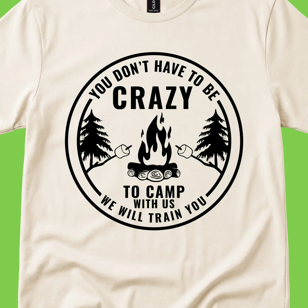 Circular badge design with campfire, pine trees, and marshmallows on sticks with humorous camping text about training crazy campers