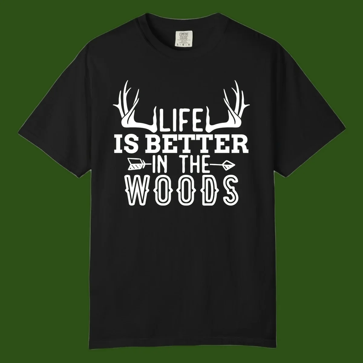 White text reading 'Life Is Better In The Woods' with deer antlers and arrows on gray background