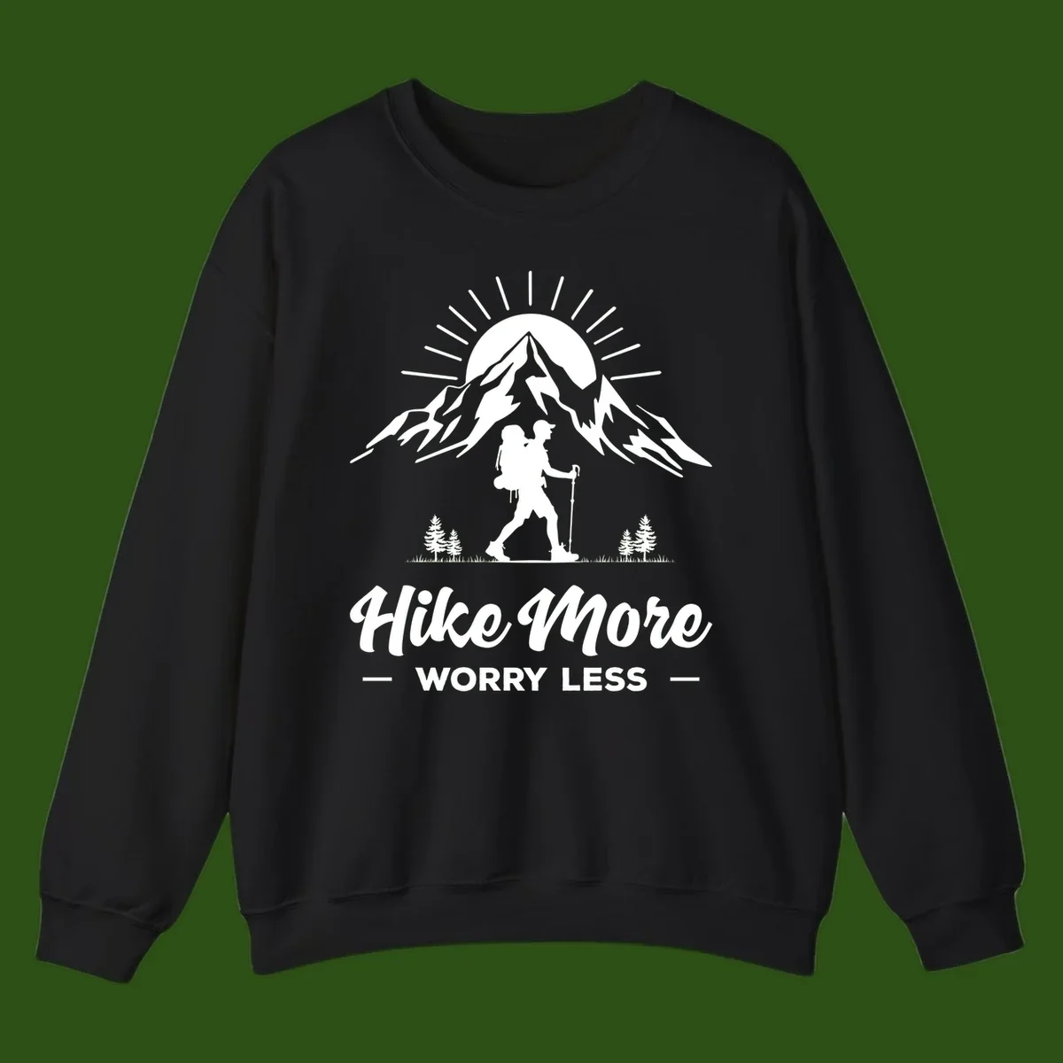 Silhouette of hiker with backpack and poles facing snow-capped mountain with radiating sun, evergreen trees below, text reads 'Hike More Worry Less'