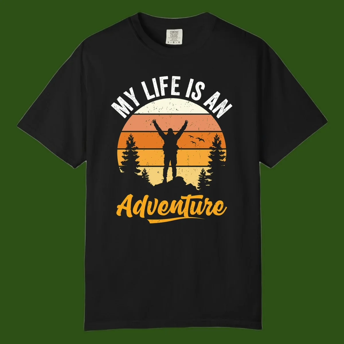Retro sunset illustration with silhouette of person celebrating arms raised, evergreen trees and mountains, text 'My Life Is An Adventure'