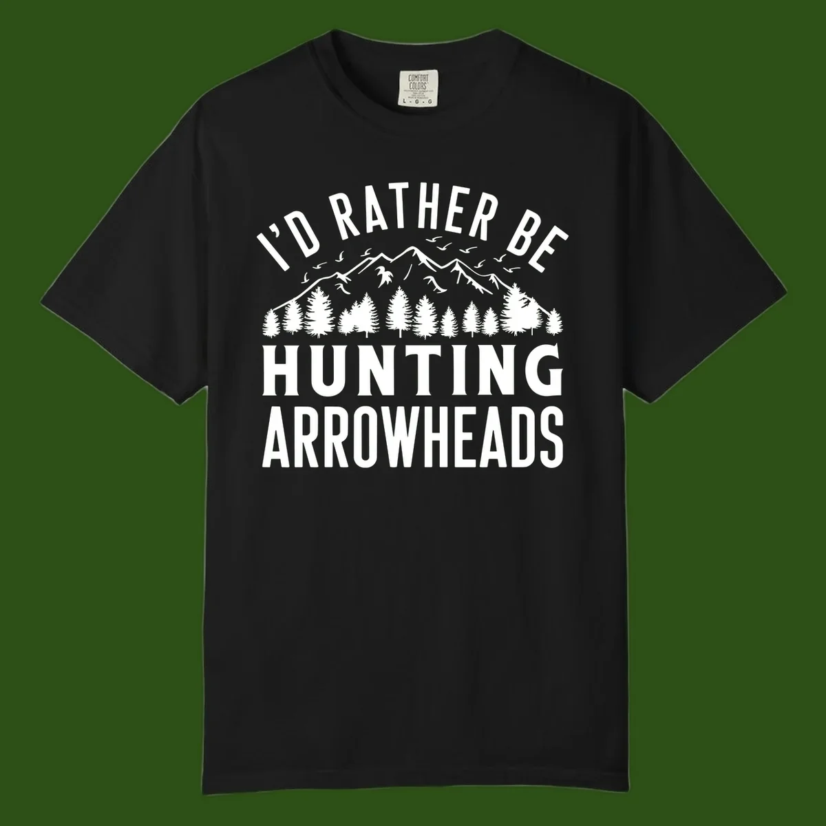 Mountain landscape with evergreen trees and birds, white text reading 'I'd Rather Be Hunting Arrowheads' on gray background