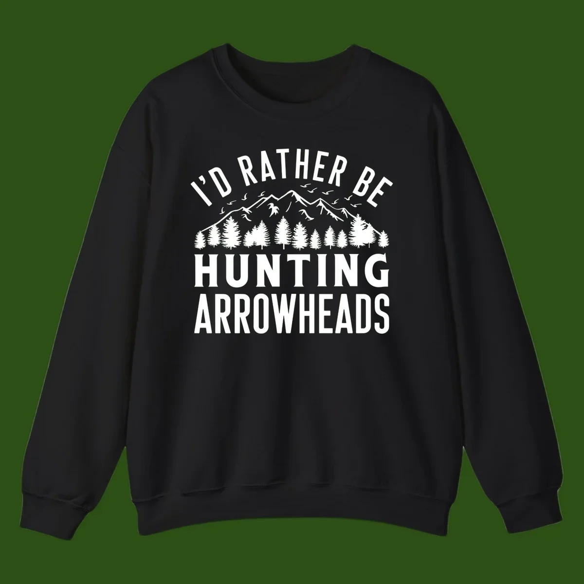 Mountain landscape with evergreen trees and birds, white text reading 'I'd Rather Be Hunting Arrowheads' on gray background