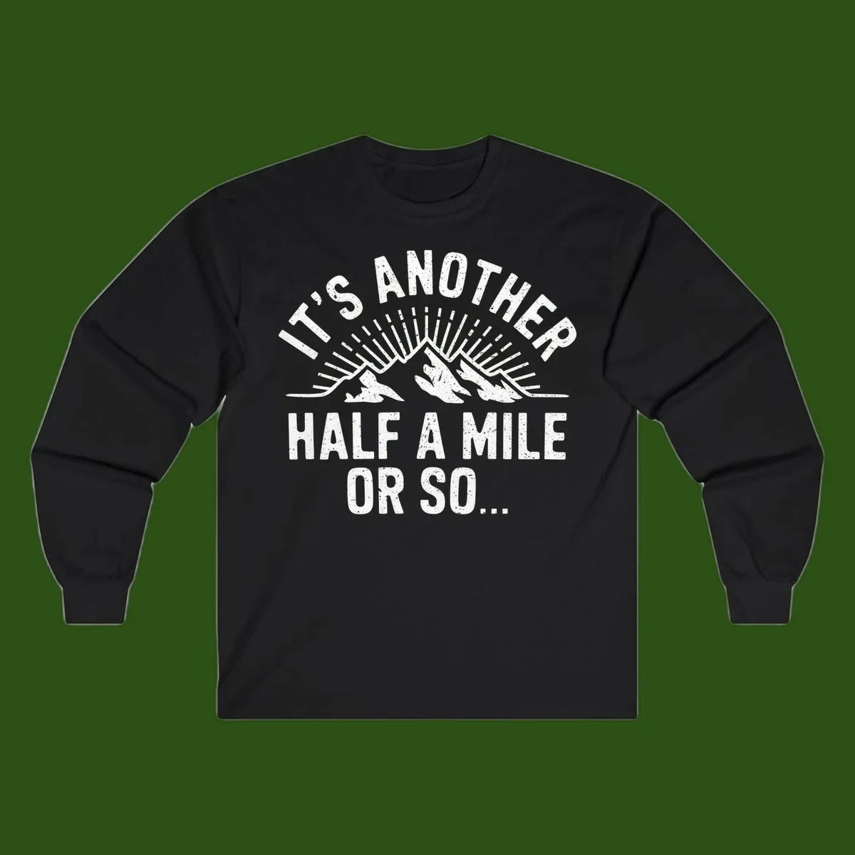 Retro distressed design with mountain peaks and sun rays, text reads 'It's Another Half A Mile Or So' - humorous hiking and camping artwork
