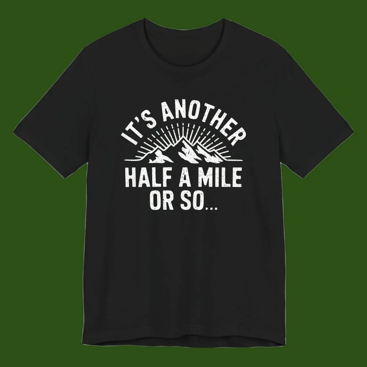 Retro distressed design with mountain peaks and sun rays, text reads 'It's Another Half A Mile Or So' - humorous hiking and camping artwork