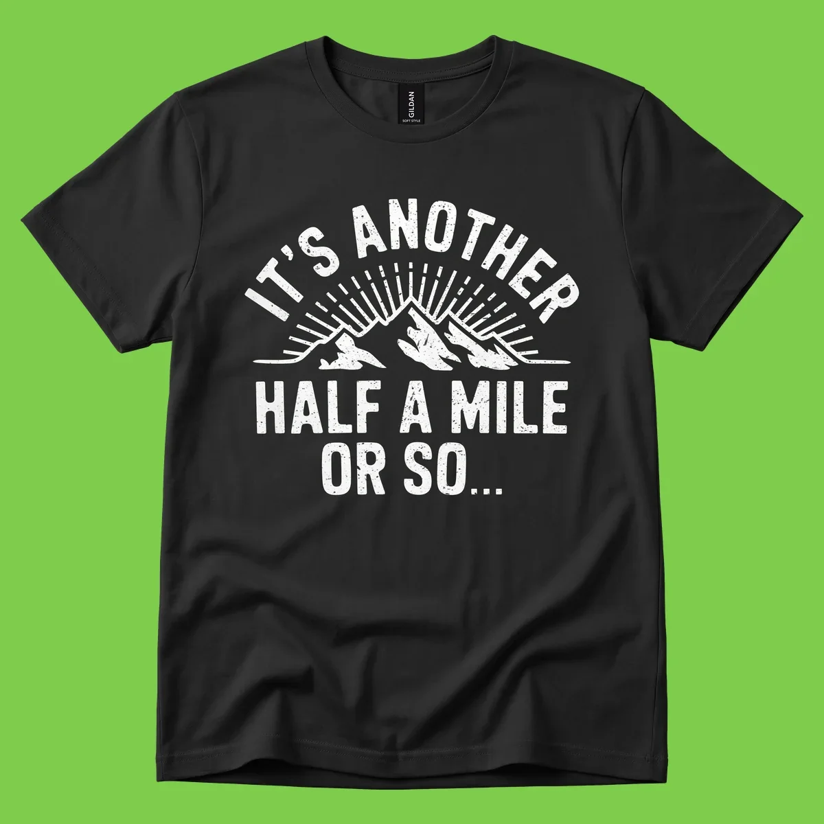 Retro distressed design with mountain peaks and sun rays, text reads 'It's Another Half A Mile Or So' - humorous hiking and camping artwork