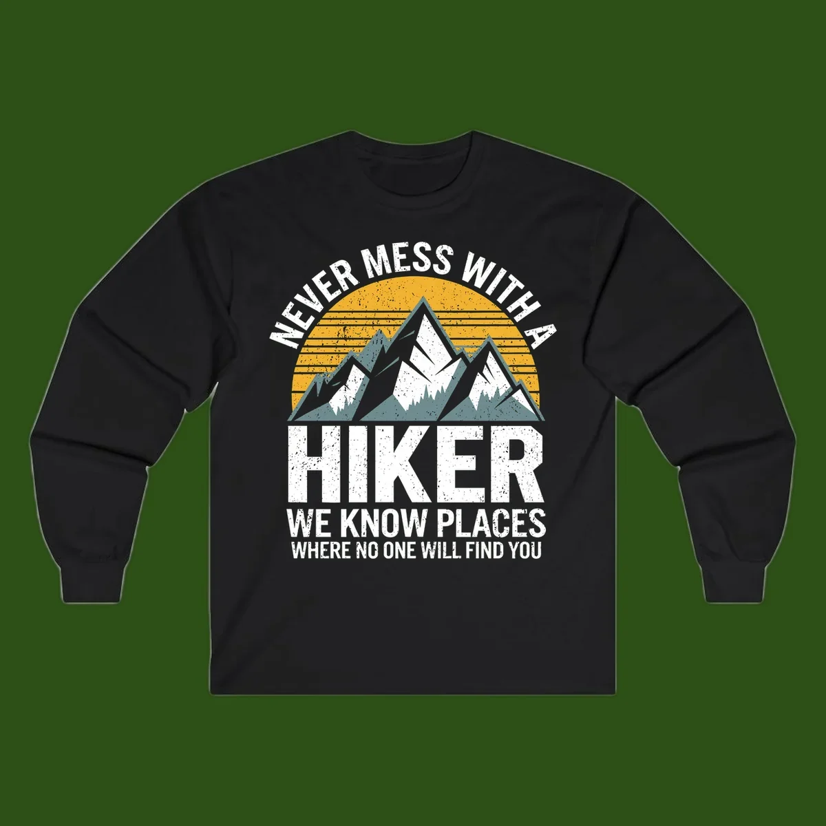 Vintage-style design with snow-capped mountains and forest silhouette against striped sunset, text reads 'Never Mess With A Hiker We Know Places Where No One Will Find You'