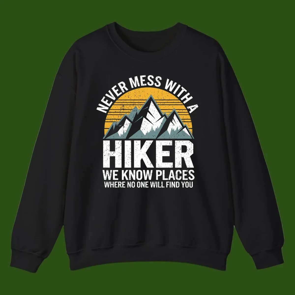 Vintage-style design with snow-capped mountains and forest silhouette against striped sunset, text reads 'Never Mess With A Hiker We Know Places Where No One Will Find You'
