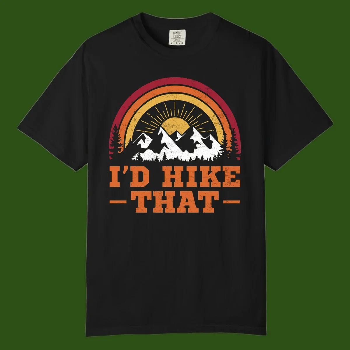 Vintage badge design with snow-capped mountains, evergreen trees, golden sun rays, and text reading 'I'd Hike That' in retro style