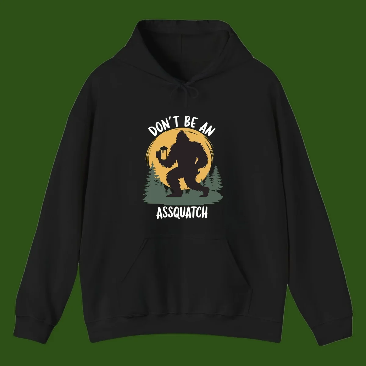 Black silhouette of Bigfoot holding a beer mug under a full moon with pine trees, text reads don't be an assquatch