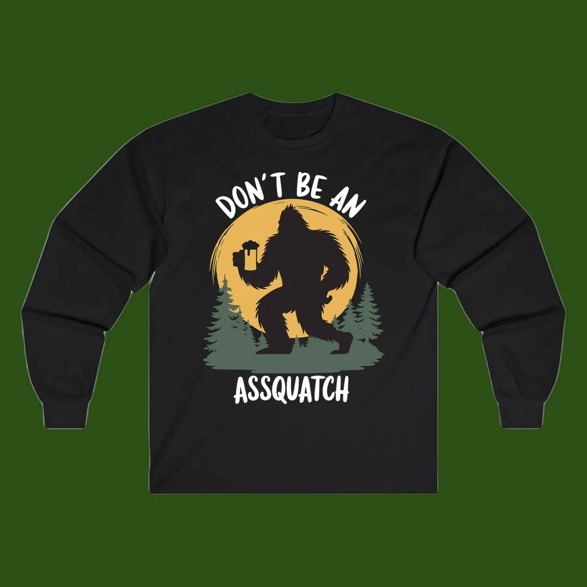 Black silhouette of Bigfoot holding a beer mug under a full moon with pine trees, text reads don't be an assquatch