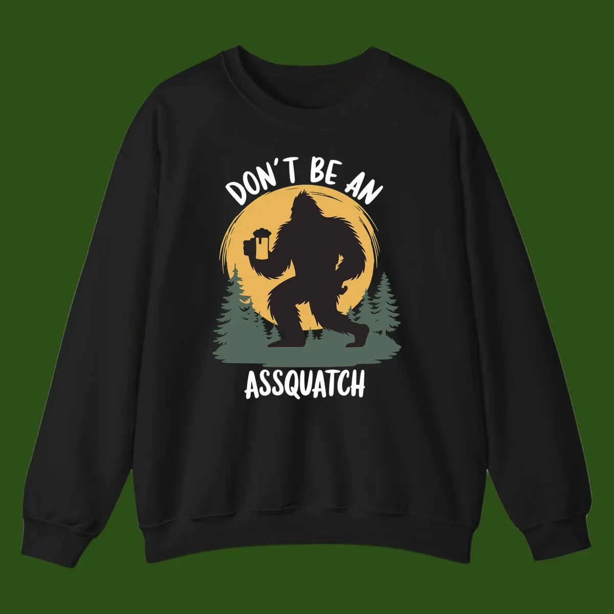 Black silhouette of Bigfoot holding a beer mug under a full moon with pine trees, text reads don't be an assquatch