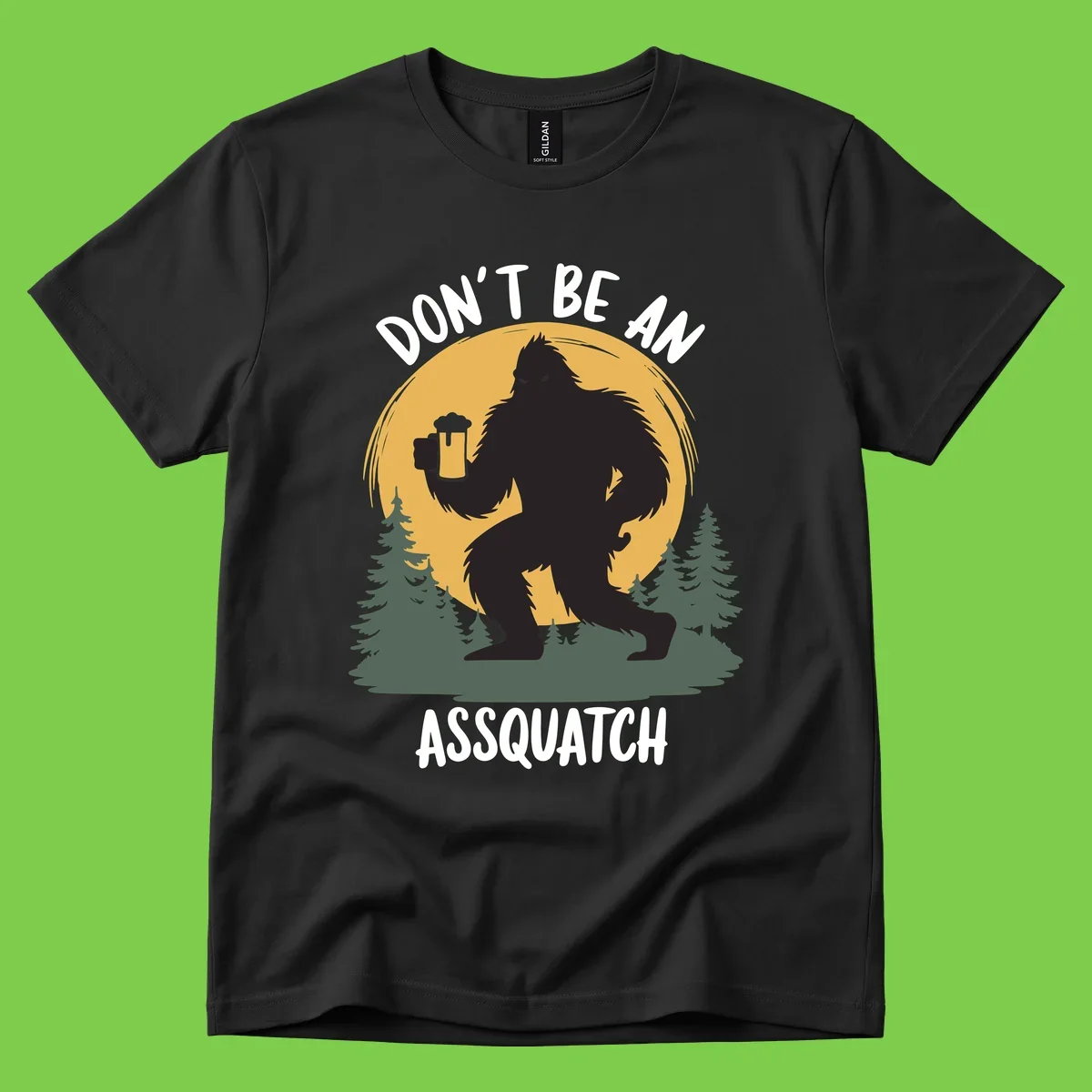 Black silhouette of Bigfoot holding a beer mug under a full moon with pine trees, text reads don't be an assquatch