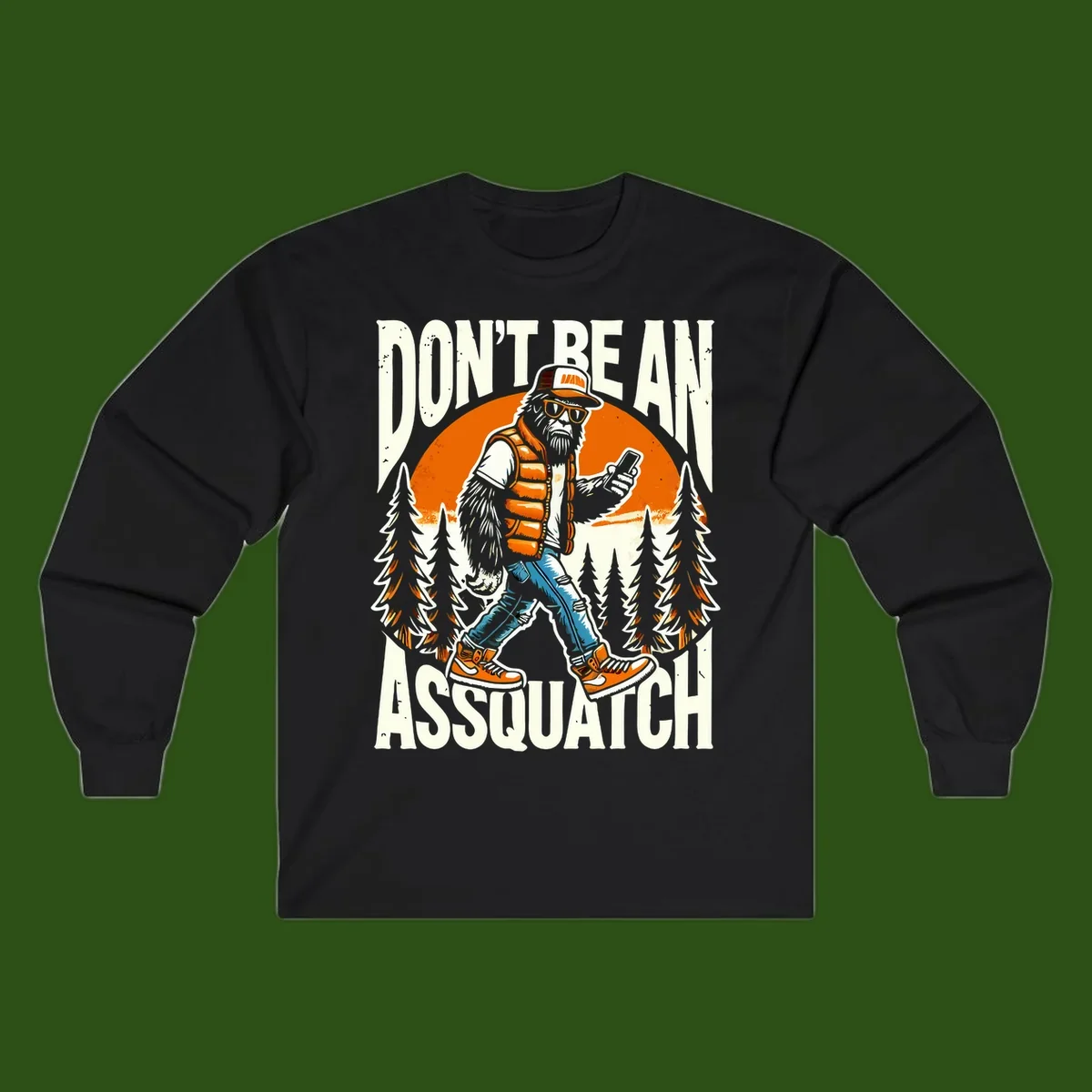 Cartoon sasquatch in hiking gear with backpack and smartphone, 'Don't Be An Assquatch' text, forest and orange sun background.