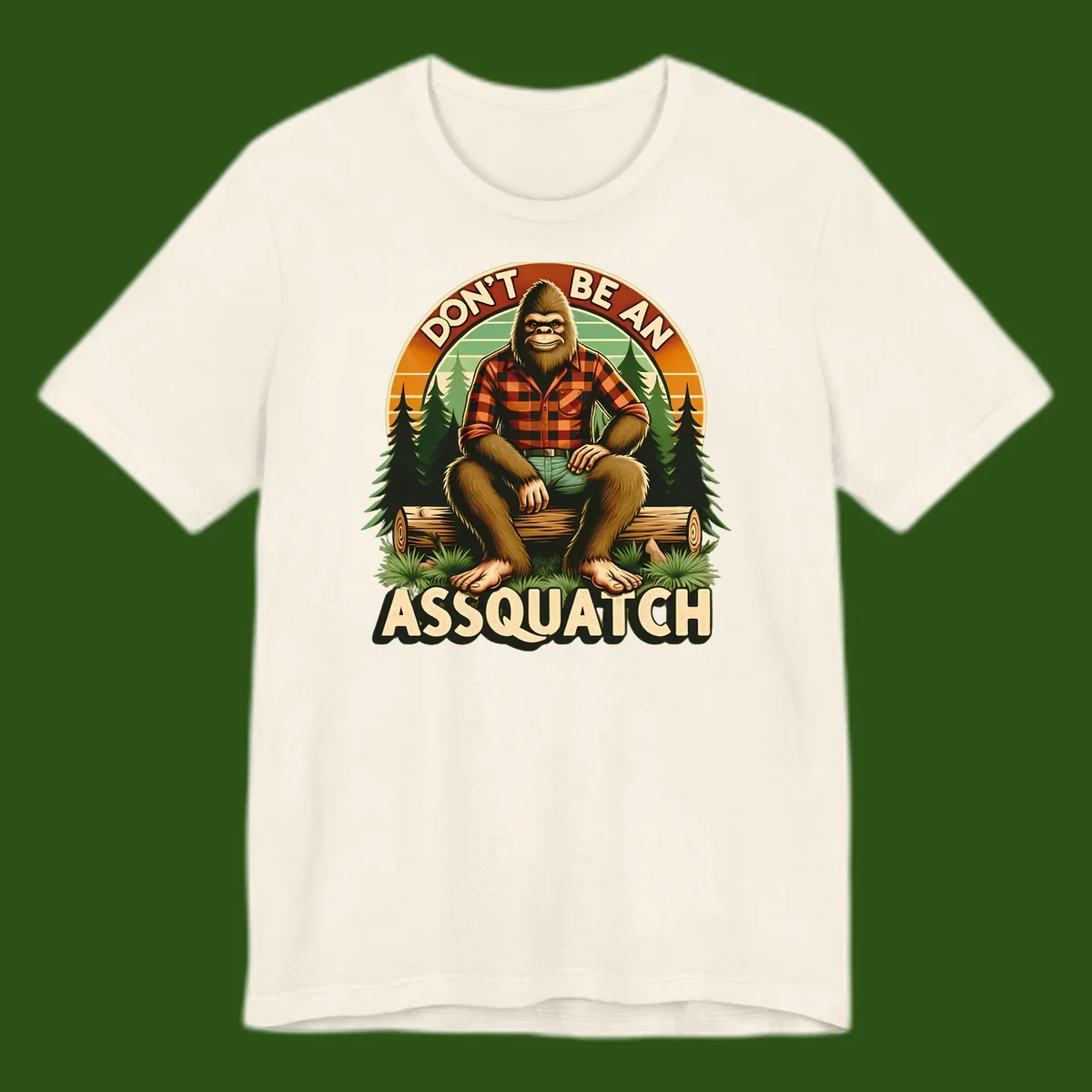 Vintage badge design with friendly Bigfoot in plaid shirt sitting on a log with forest trees, text reads 'Don't Be An Assquatch'