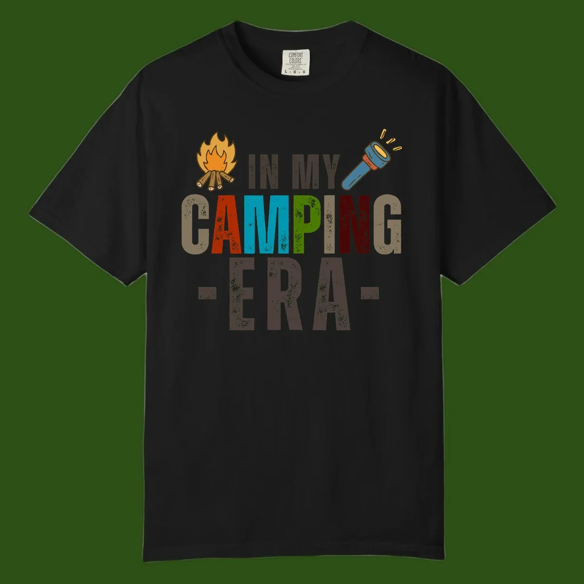 Campfire and flashlight icons flank colorful distressed text reading 'In My Camping Era' on gray background