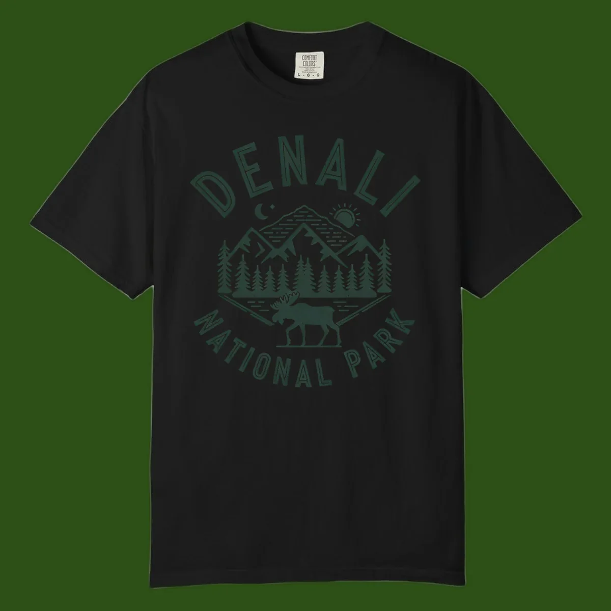 Denial National Park badge design with moose walking through forest, mountains, sun and moon with crossed fishing rods