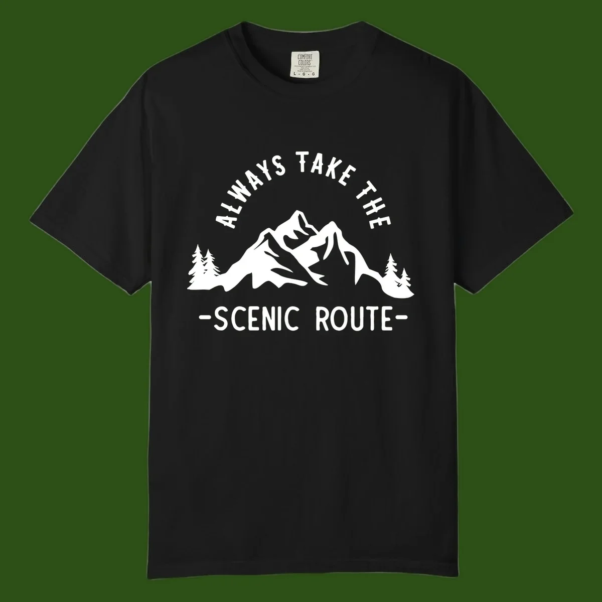 Mountain landscape with evergreen trees and text reading 'Always Take The Scenic Route' in bold lettering