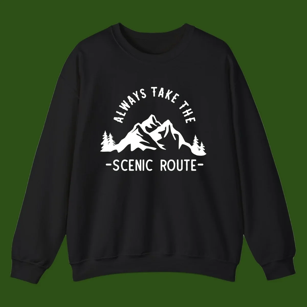 Mountain landscape with evergreen trees and text reading 'Always Take The Scenic Route' in bold lettering