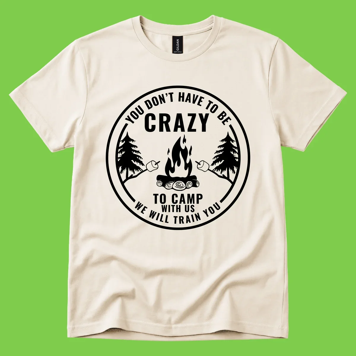 Circular badge design with campfire, pine trees, and marshmallows on sticks with humorous camping text about training crazy campers