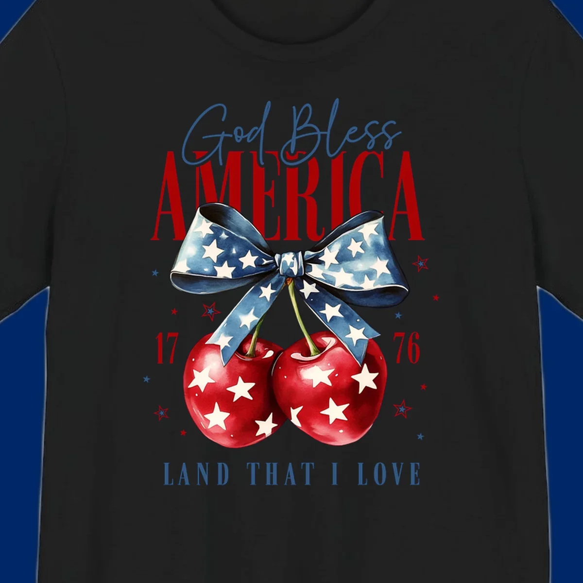 A patriotic design featuring 'God Bless AMERICA' and 'LAND THAT I LOVE' with a blue star-spangled bow, two red star-covered cherries, and the numbers '17' and '76'. god-bless-america-cherries.
