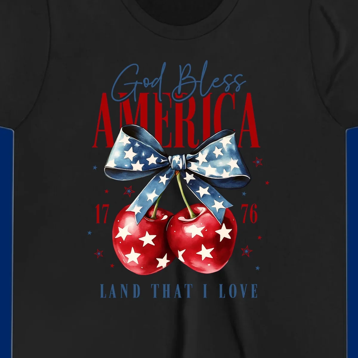 A patriotic design featuring 'God Bless AMERICA' and 'LAND THAT I LOVE' with a blue star-spangled bow, two red star-covered cherries, and the numbers '17' and '76'. god-bless-america-cherries.
