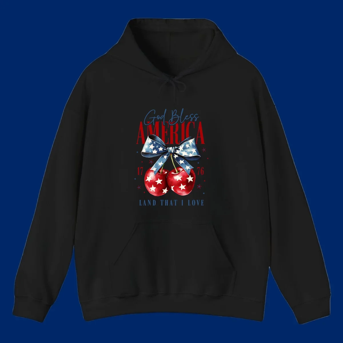 A patriotic design featuring 'God Bless AMERICA' and 'LAND THAT I LOVE' with a blue star-spangled bow, two red star-covered cherries, and the numbers '17' and '76'. god-bless-america-cherries.