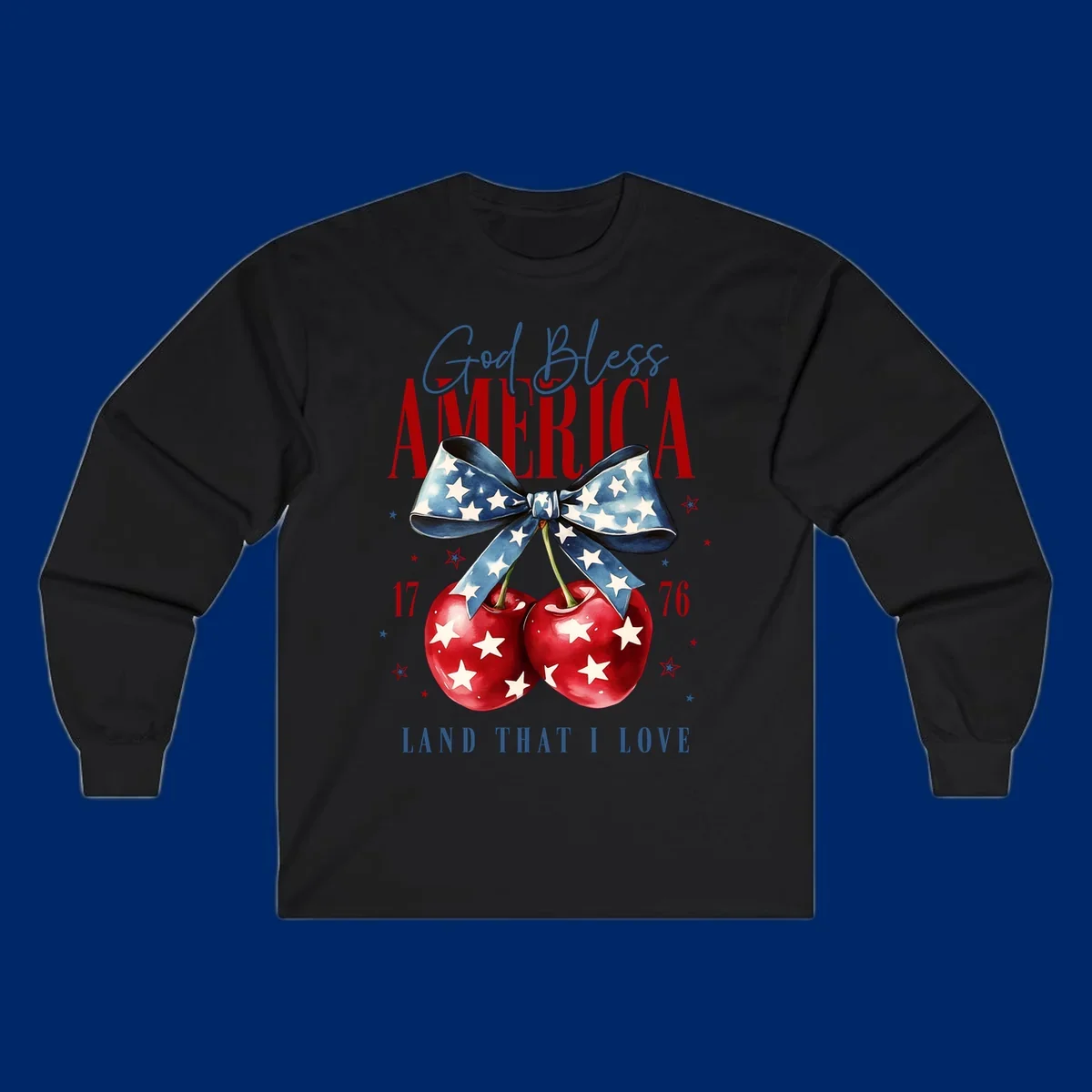 A patriotic design featuring 'God Bless AMERICA' and 'LAND THAT I LOVE' with a blue star-spangled bow, two red star-covered cherries, and the numbers '17' and '76'. god-bless-america-cherries.