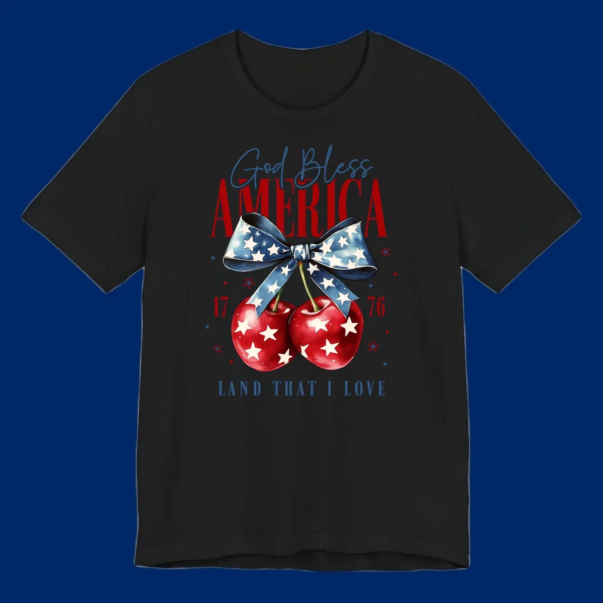 A patriotic design featuring 'God Bless AMERICA' and 'LAND THAT I LOVE' with a blue star-spangled bow, two red star-covered cherries, and the numbers '17' and '76'. god-bless-america-cherries.