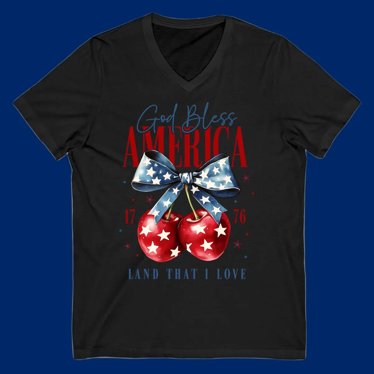 A patriotic design featuring 'God Bless AMERICA' and 'LAND THAT I LOVE' with a blue star-spangled bow, two red star-covered cherries, and the numbers '17' and '76'. god-bless-america-cherries.