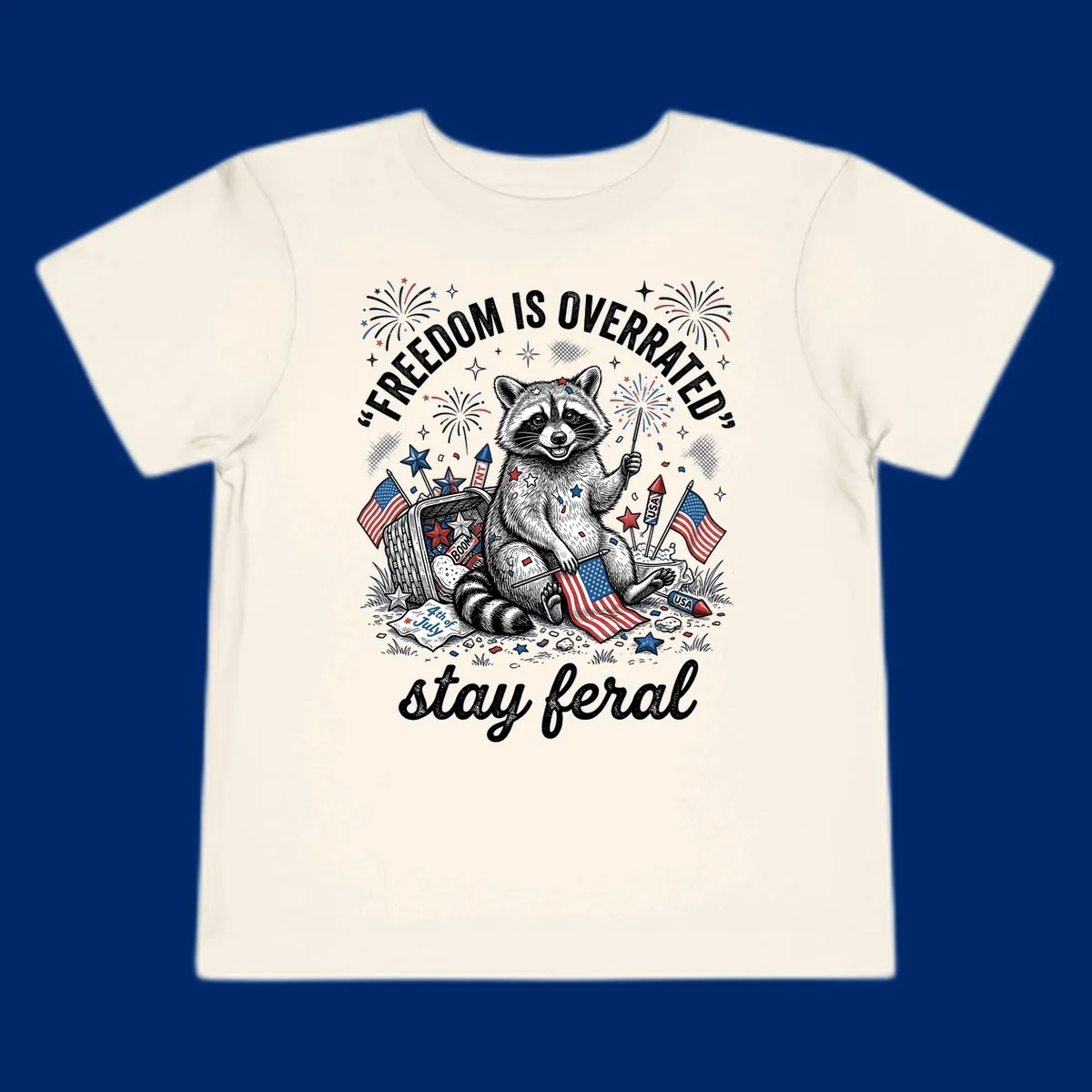 A black and white illustration of a feral raccoon celebrating July 4th with fireworks, American flags, and the text 'FREEDOM IS OVERRATED' and 'stay feral'.