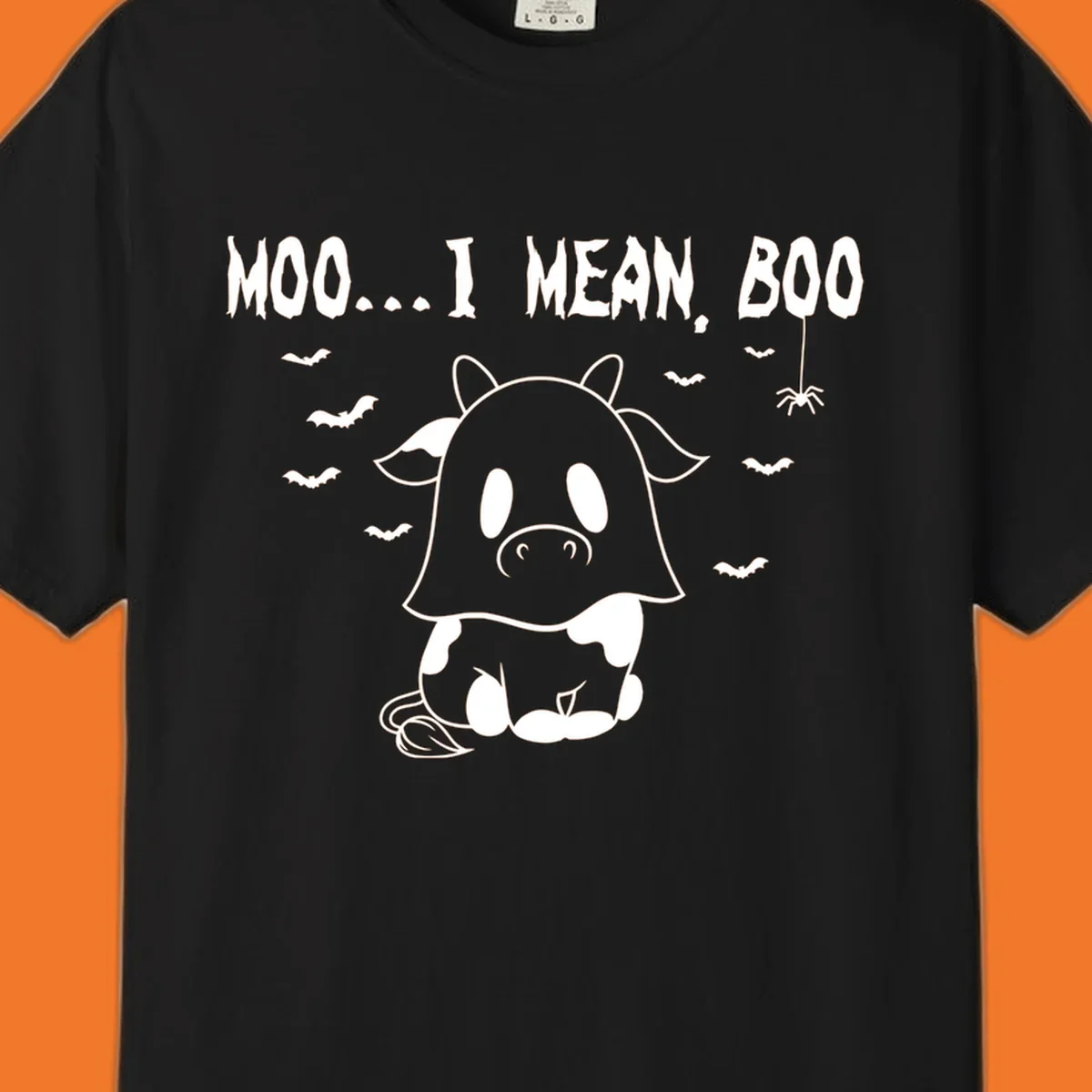 Illustration of a cow dressed as a ghost saying Moo... I mean, Boo, with bats and a spider. Moo-boo-cow.