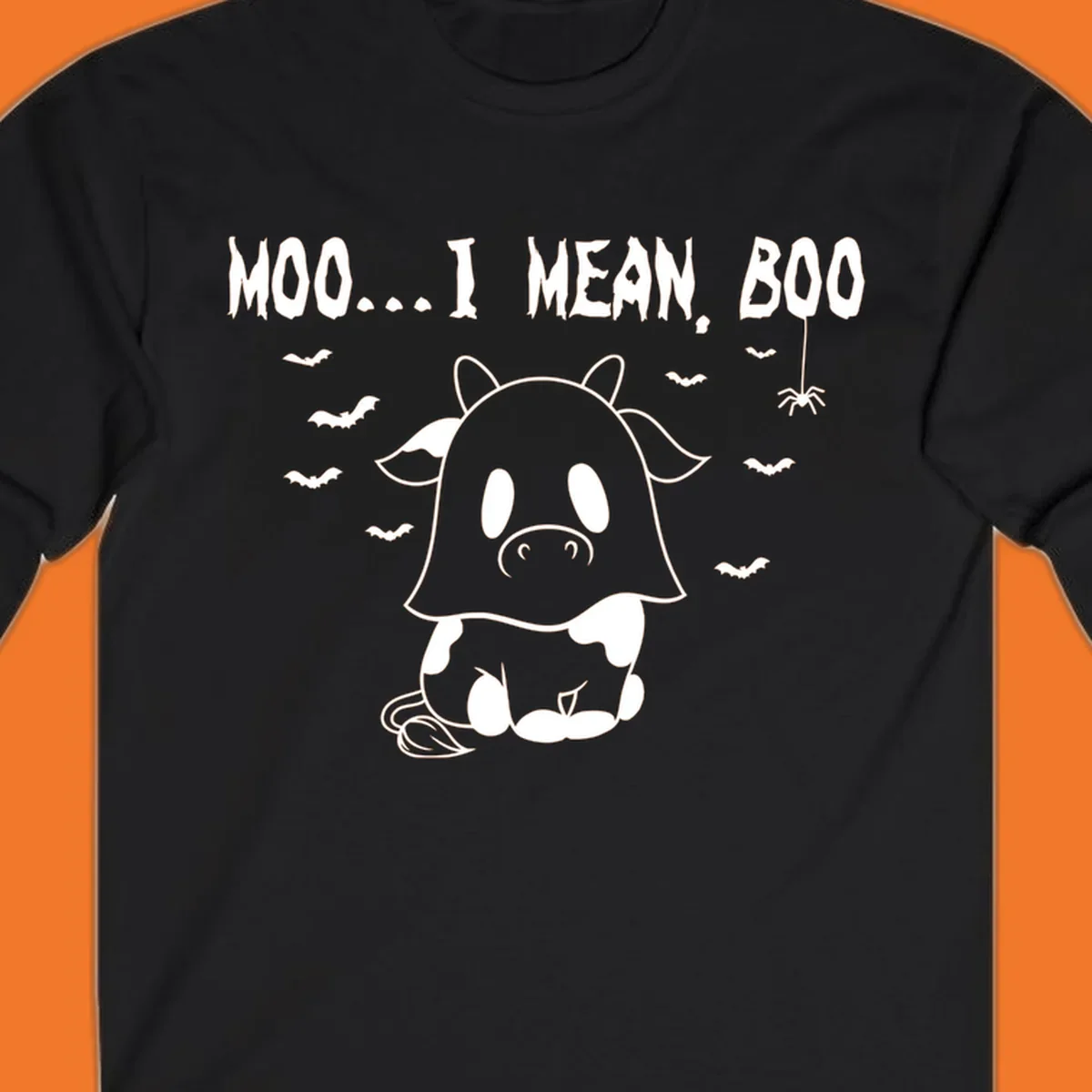 Illustration of a cow dressed as a ghost saying Moo... I mean, Boo, with bats and a spider. Moo-boo-cow.