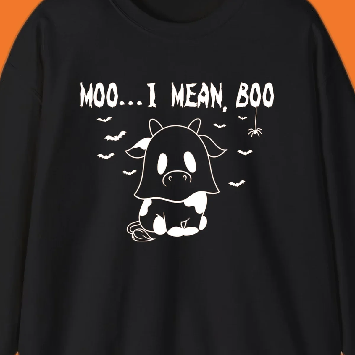Illustration of a cow dressed as a ghost saying Moo... I mean, Boo, with bats and a spider. Moo-boo-cow.