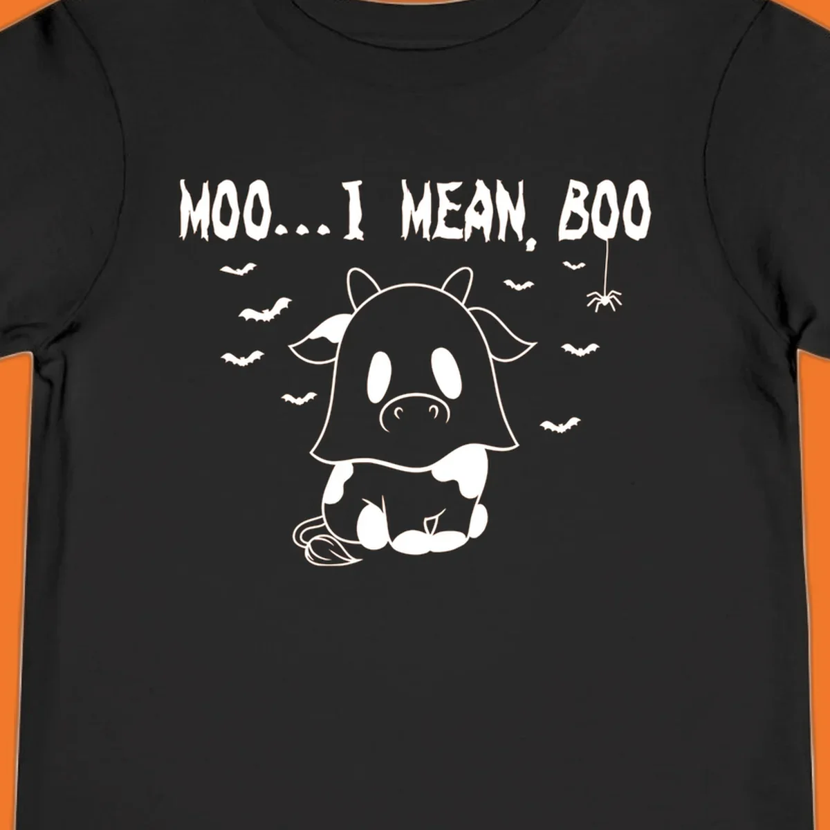 Illustration of a cow dressed as a ghost saying Moo... I mean, Boo, with bats and a spider. Moo-boo-cow.