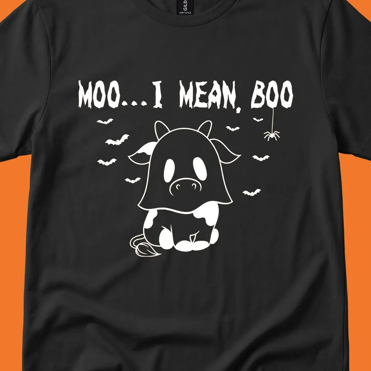 Illustration of a cow dressed as a ghost saying Moo... I mean, Boo, with bats and a spider. Moo-boo-cow.