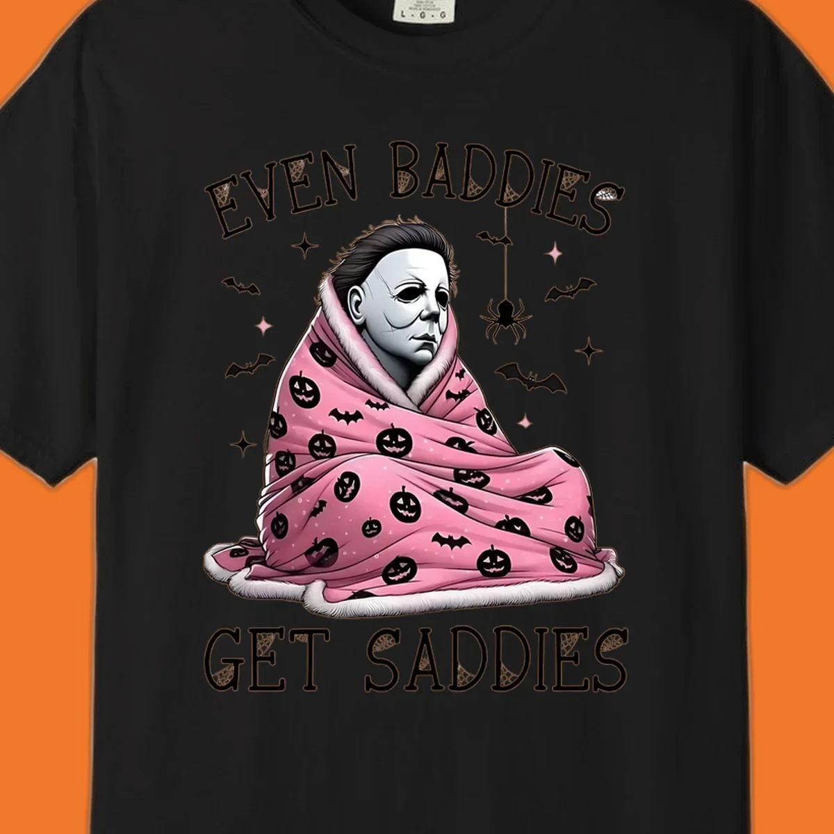 Michael Myers in a pink pumpkin blanket with text 'EVEN BADDIES GET SADDIES', for the michael-myers-cozy concept.