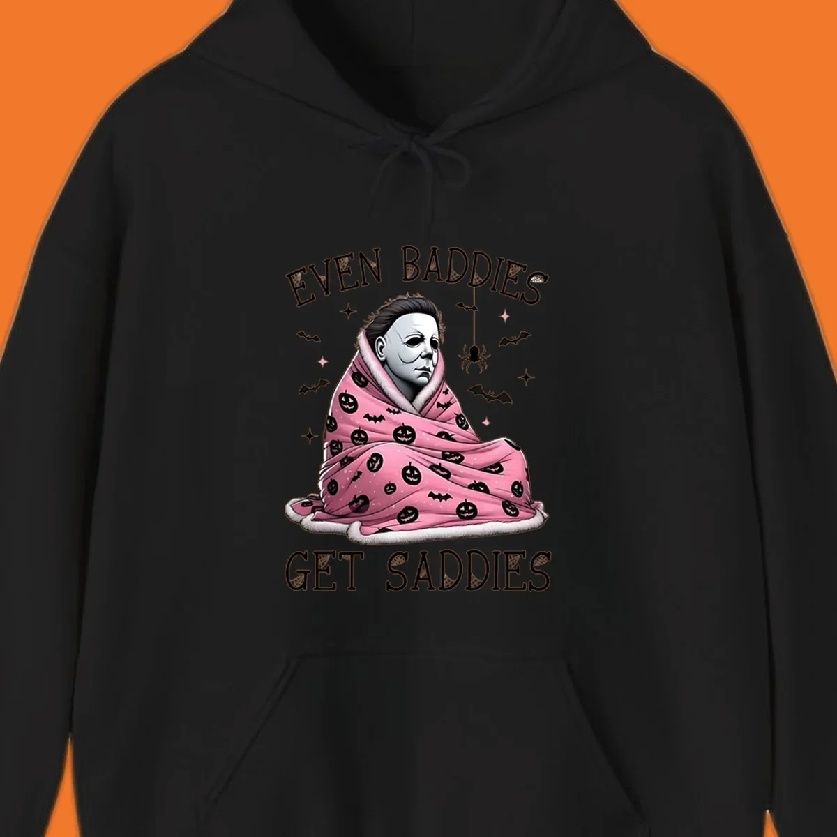 Michael Myers in a pink pumpkin blanket with text 'EVEN BADDIES GET SADDIES', for the michael-myers-cozy concept.
