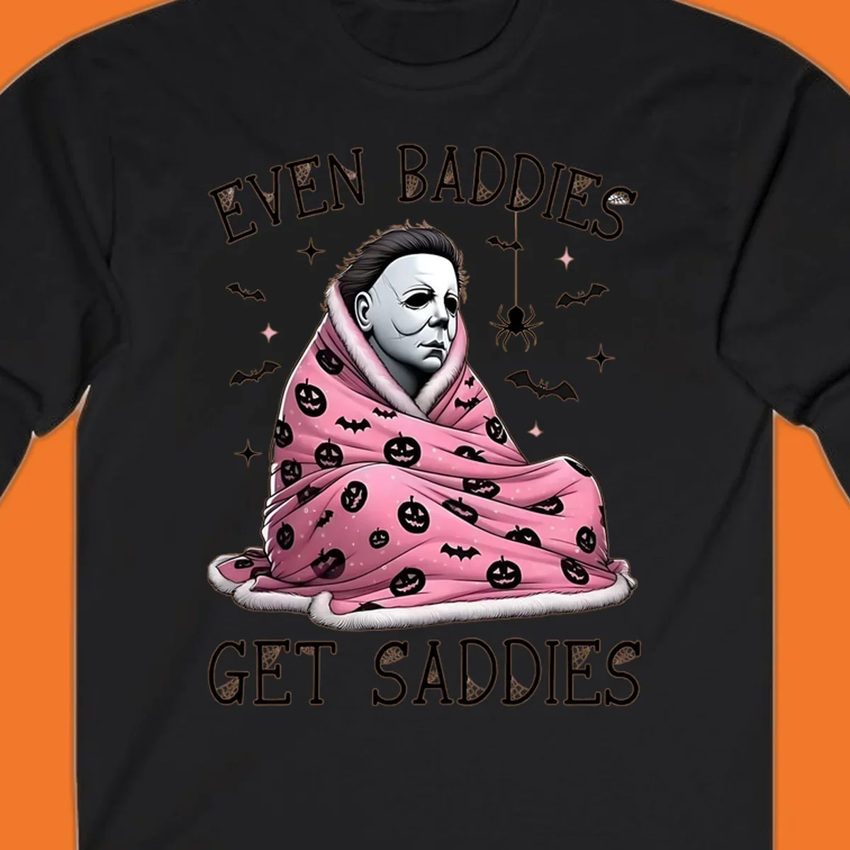 Michael Myers in a pink pumpkin blanket with text 'EVEN BADDIES GET SADDIES', for the michael-myers-cozy concept.
