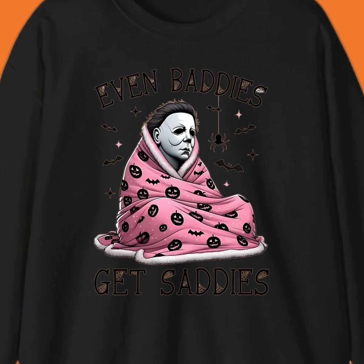 Michael Myers in a pink pumpkin blanket with text 'EVEN BADDIES GET SADDIES', for the michael-myers-cozy concept.
