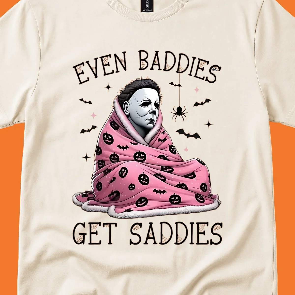 Michael Myers in a pink pumpkin blanket with text 'EVEN BADDIES GET SADDIES', for the michael-myers-cozy concept.