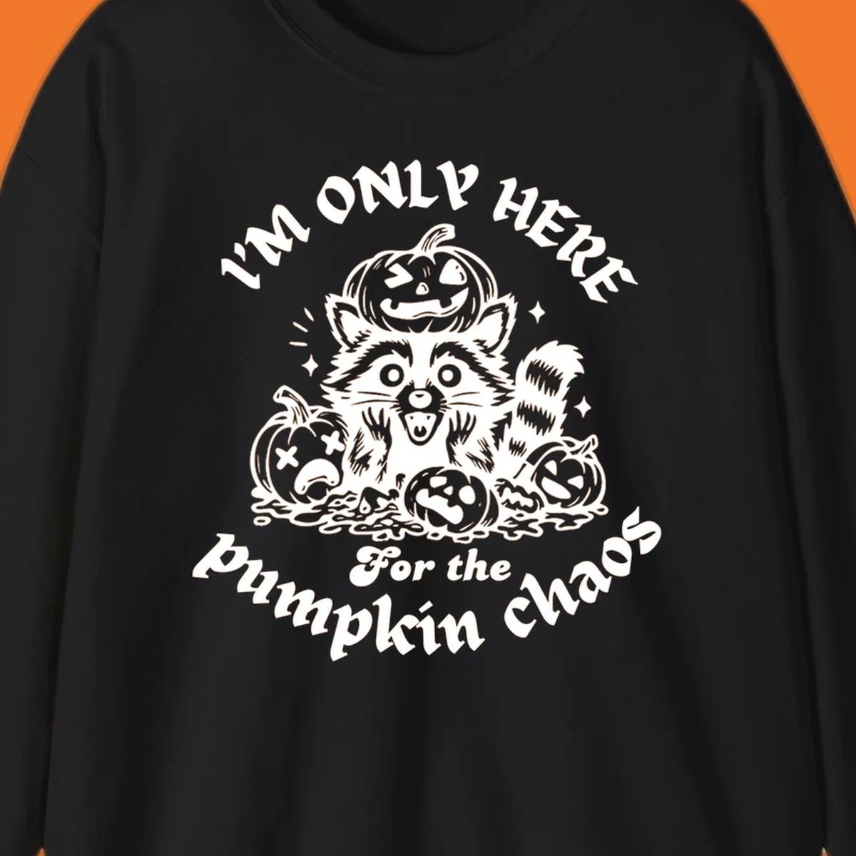 Illustration of a raccoon surrounded by pumpkins, text says 'I'm Only Here For The Pumpkin Chaos'.