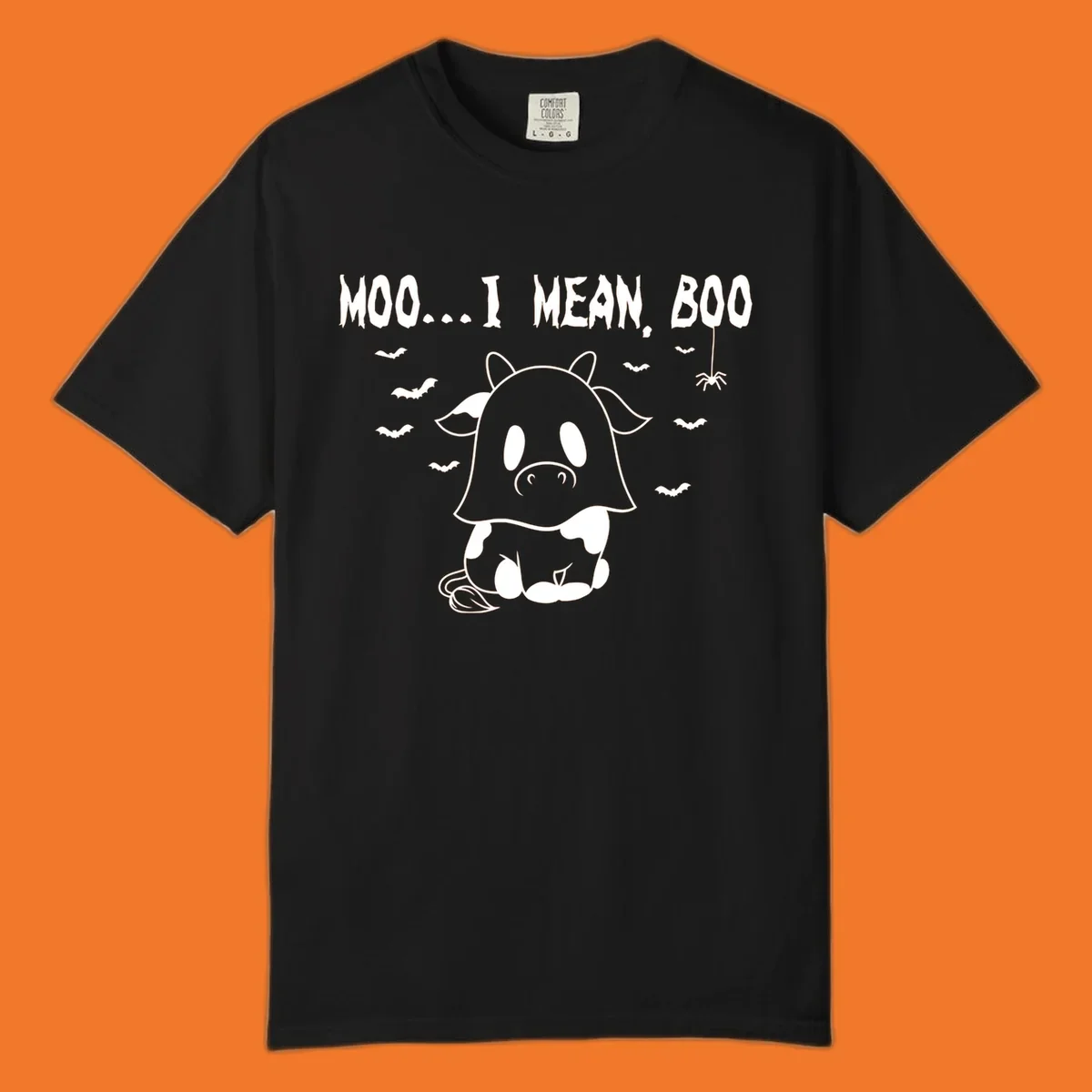 Illustration of a cow dressed as a ghost saying Moo... I mean, Boo, with bats and a spider. Moo-boo-cow.