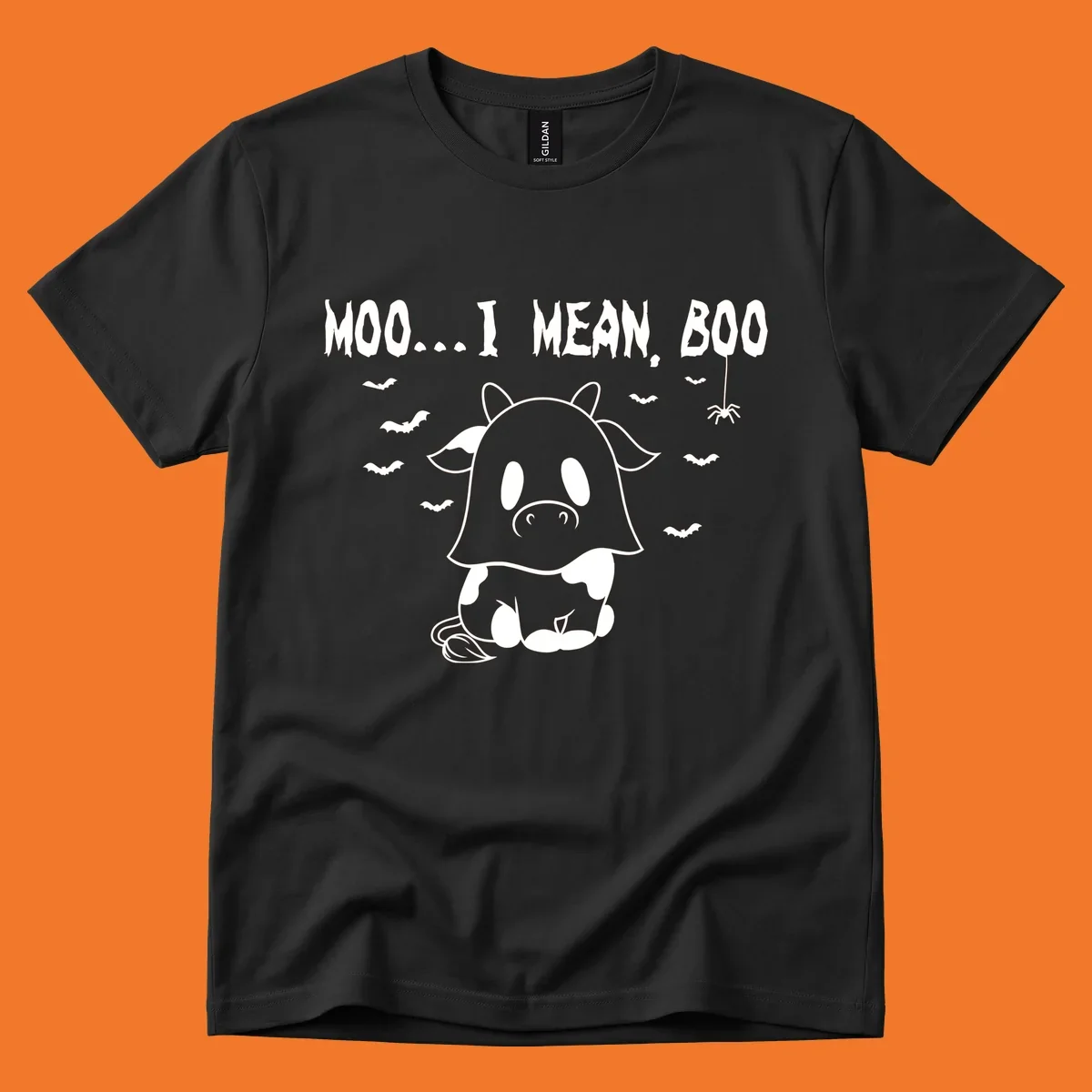 Illustration of a cow dressed as a ghost saying Moo... I mean, Boo, with bats and a spider. Moo-boo-cow.