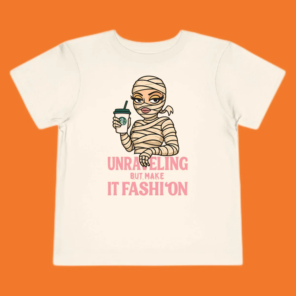 Mummy holding coffee cup with 'Unraveling But Make It Fashion' text. Mummy-fashion-coffee.