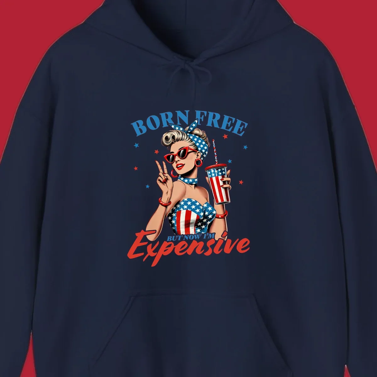 A vintage pin-up girl with a patriotic outfit and cup, making a peace sign, with the text "Born Free But Now I'm Expensive". This born-free-expensive-pinup design is surrounded by stars.