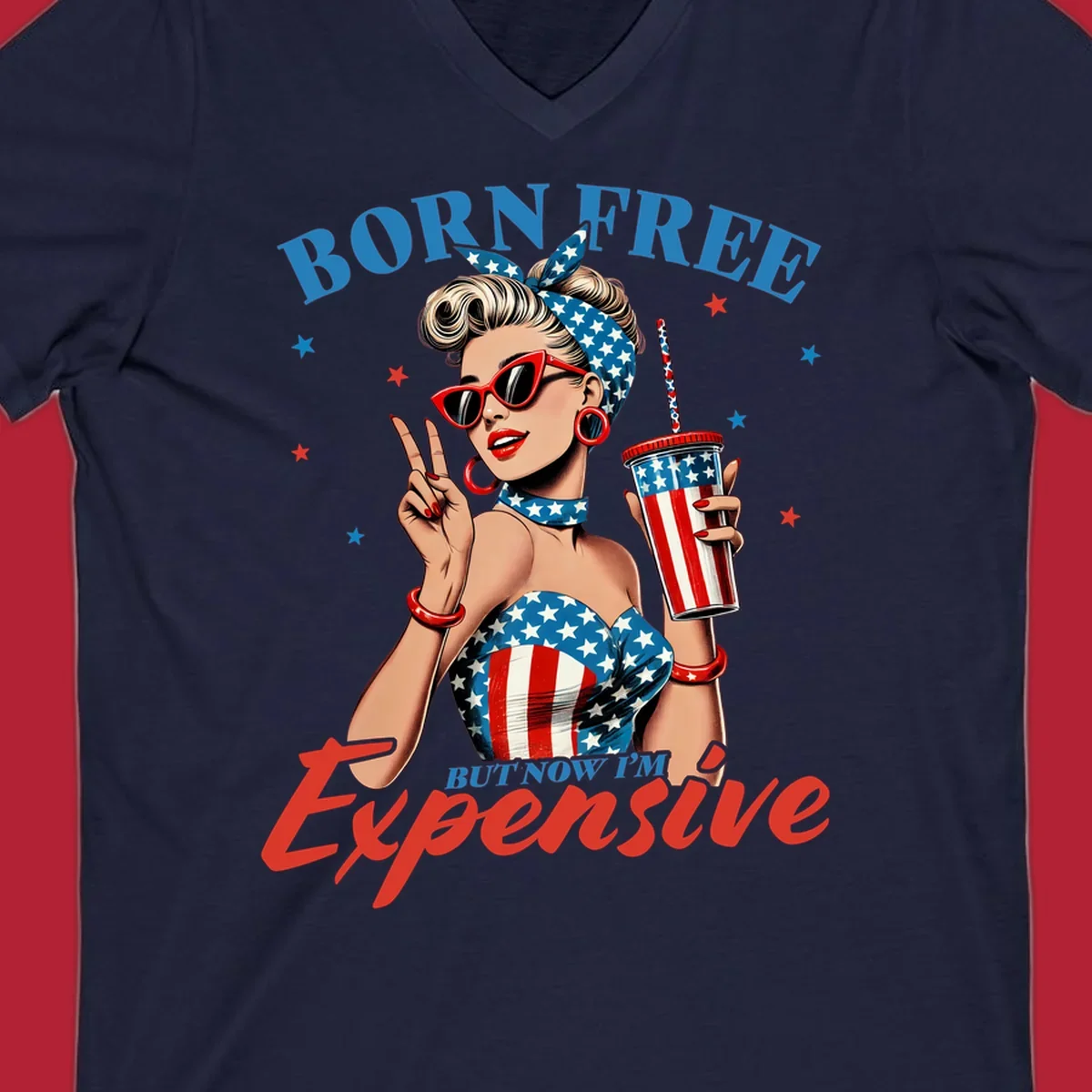 A vintage pin-up girl with a patriotic outfit and cup, making a peace sign, with the text "Born Free But Now I'm Expensive". This born-free-expensive-pinup design is surrounded by stars.